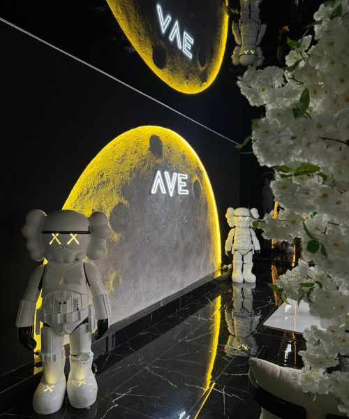 Die beleuchtete Mondwand mit AVE-Neonschriftzug und Sammlerfiguren auf schwarzem Marmor.
